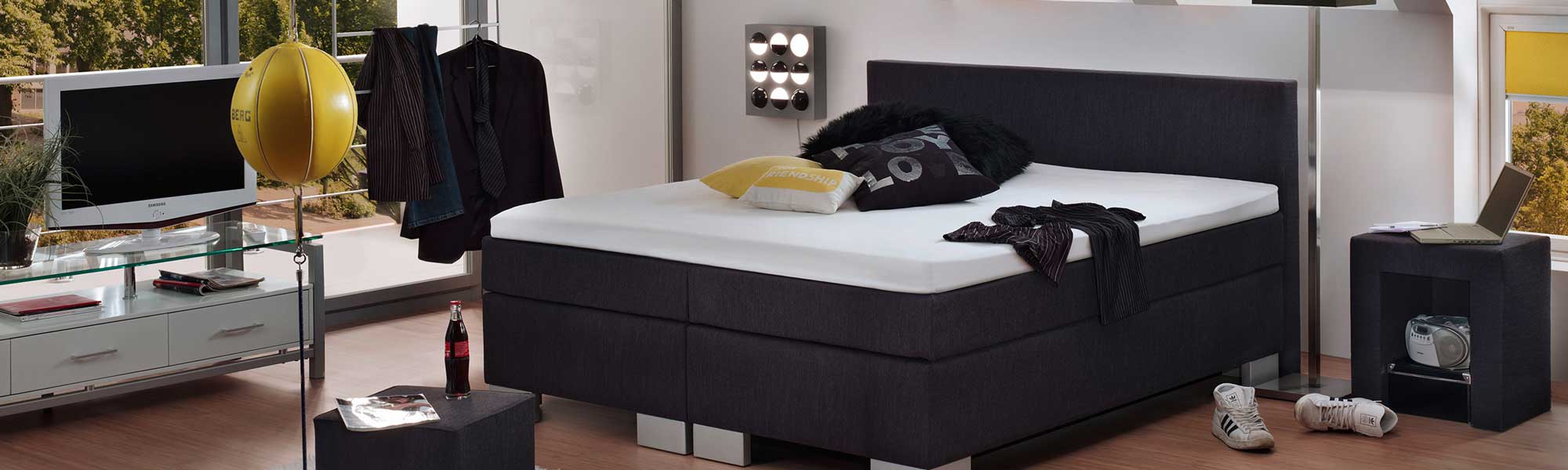 Schlafzimmer mit einem Bett, einer Kommode und einem Fernseher.