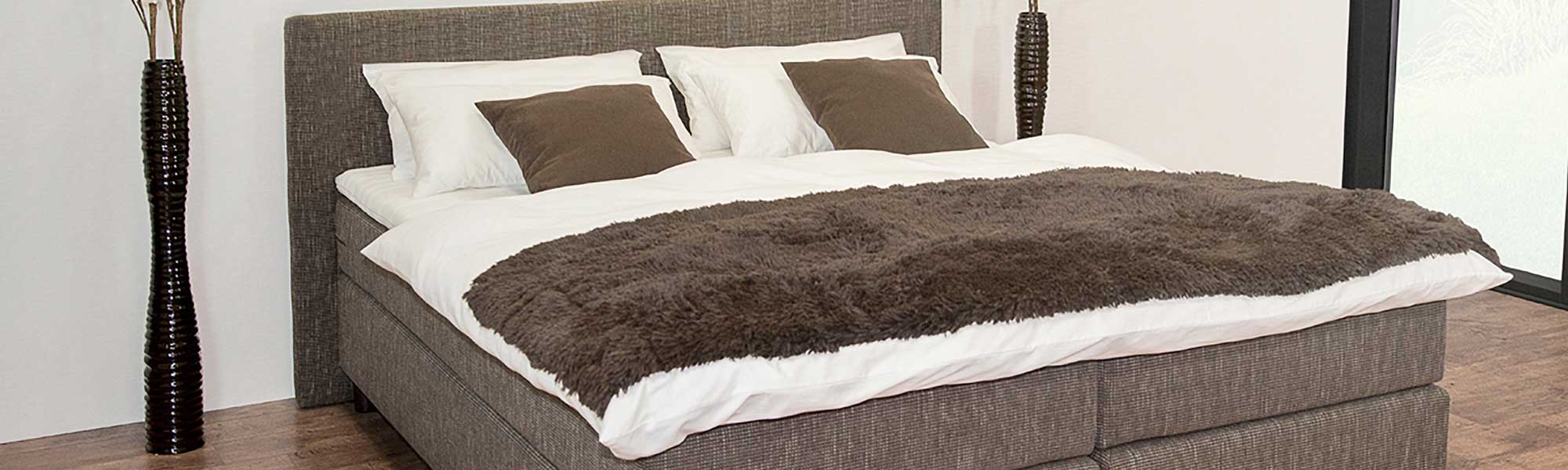 Bett mit einem Kopf- und Fussteil aus weissem und braunem Material.