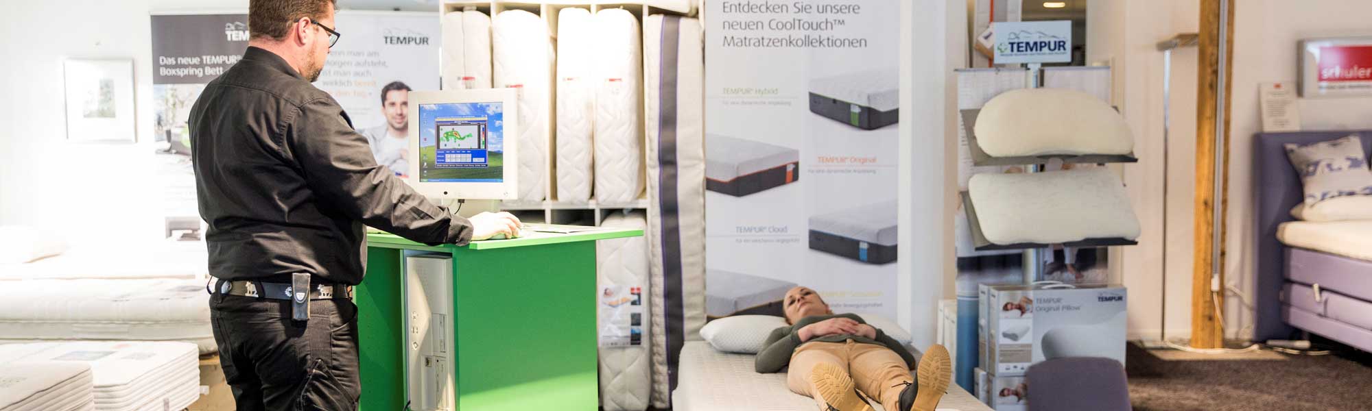 Ein Mann positioniert sich vor einem Bett in einem Raum.