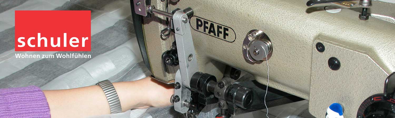 Eine Person benutzt eine Nähmaschine mit Schriftzug drauf.