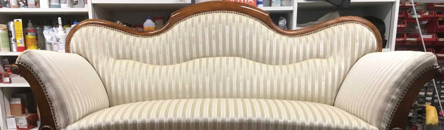 Ein Sofa mit einer weissen, gepolsterten Sitzfläche und Rücken.